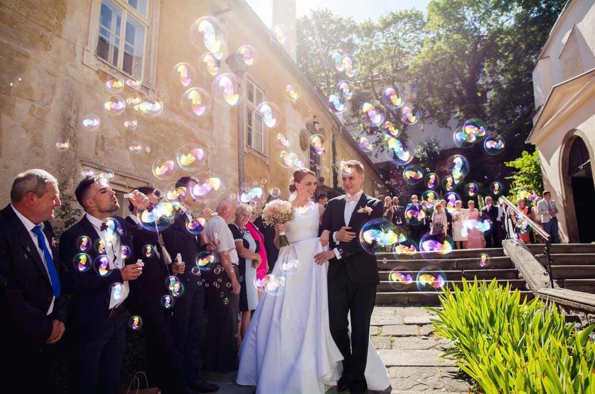 Novomanželé procházejí mezi hosty a bublinami v Mikulově
